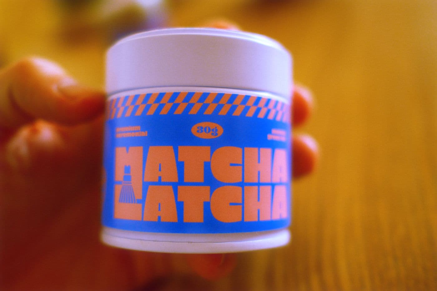 Puszka Matcha Latcha w dłoni o zachodzie słońca